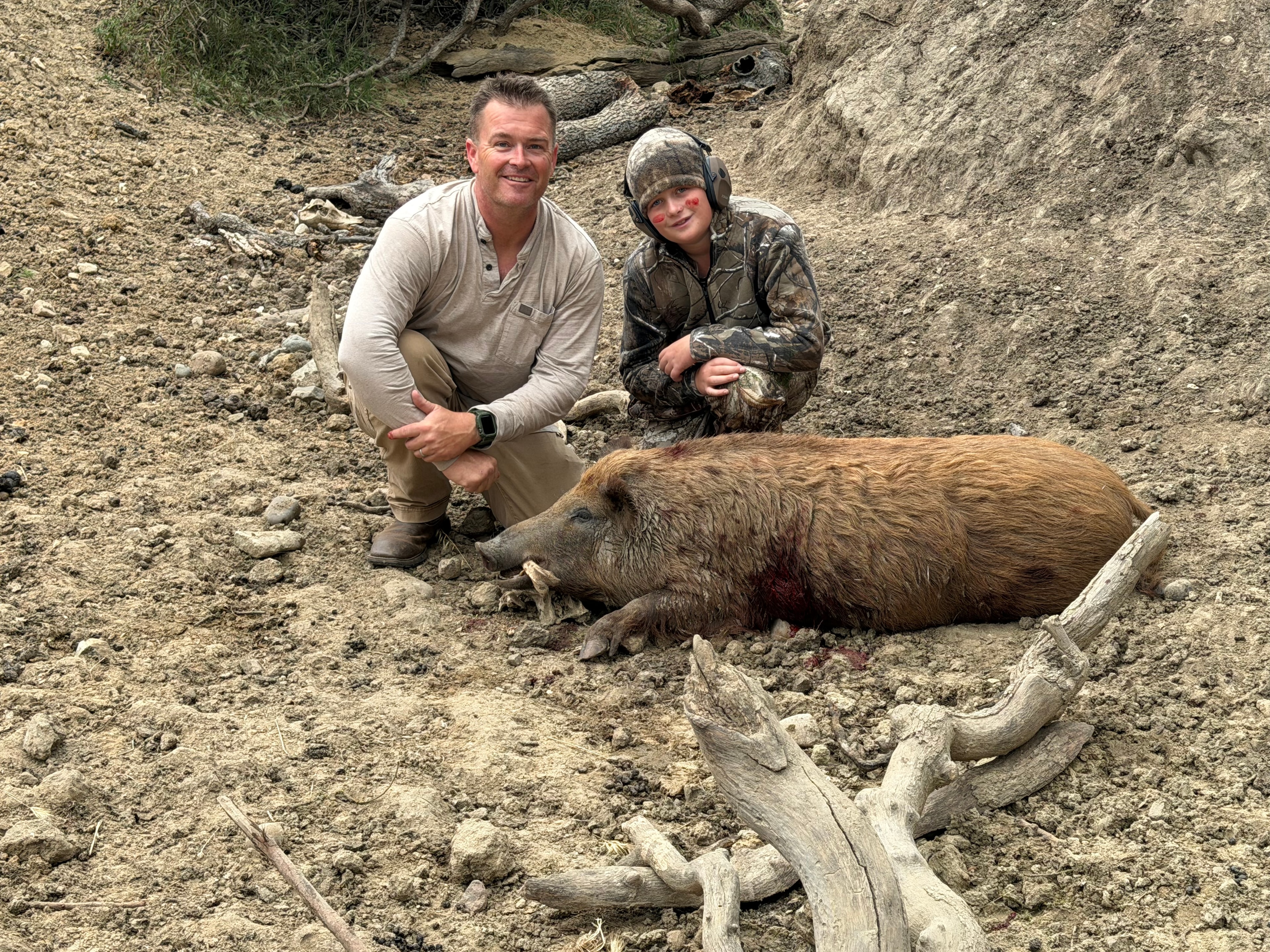 Father and son with harvested wild hog