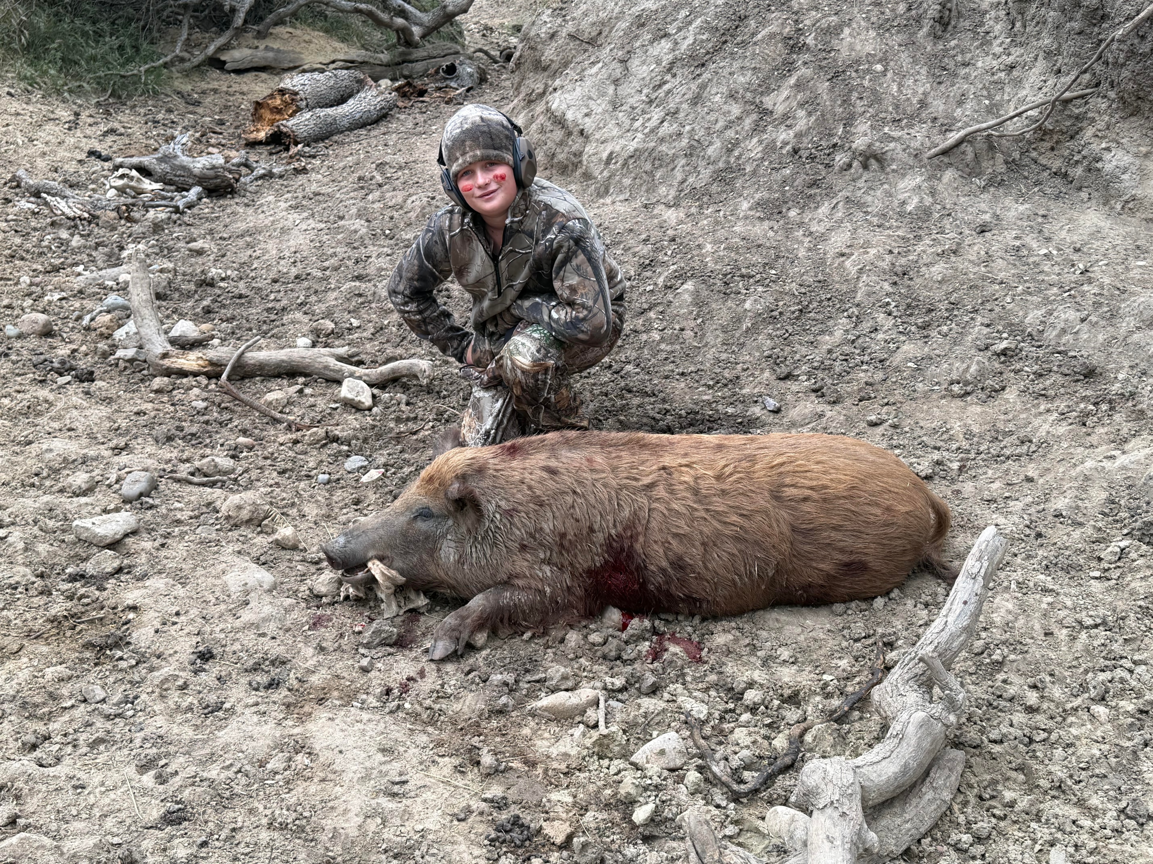 Young hunter with harvested wild hog on first guided pig hunt