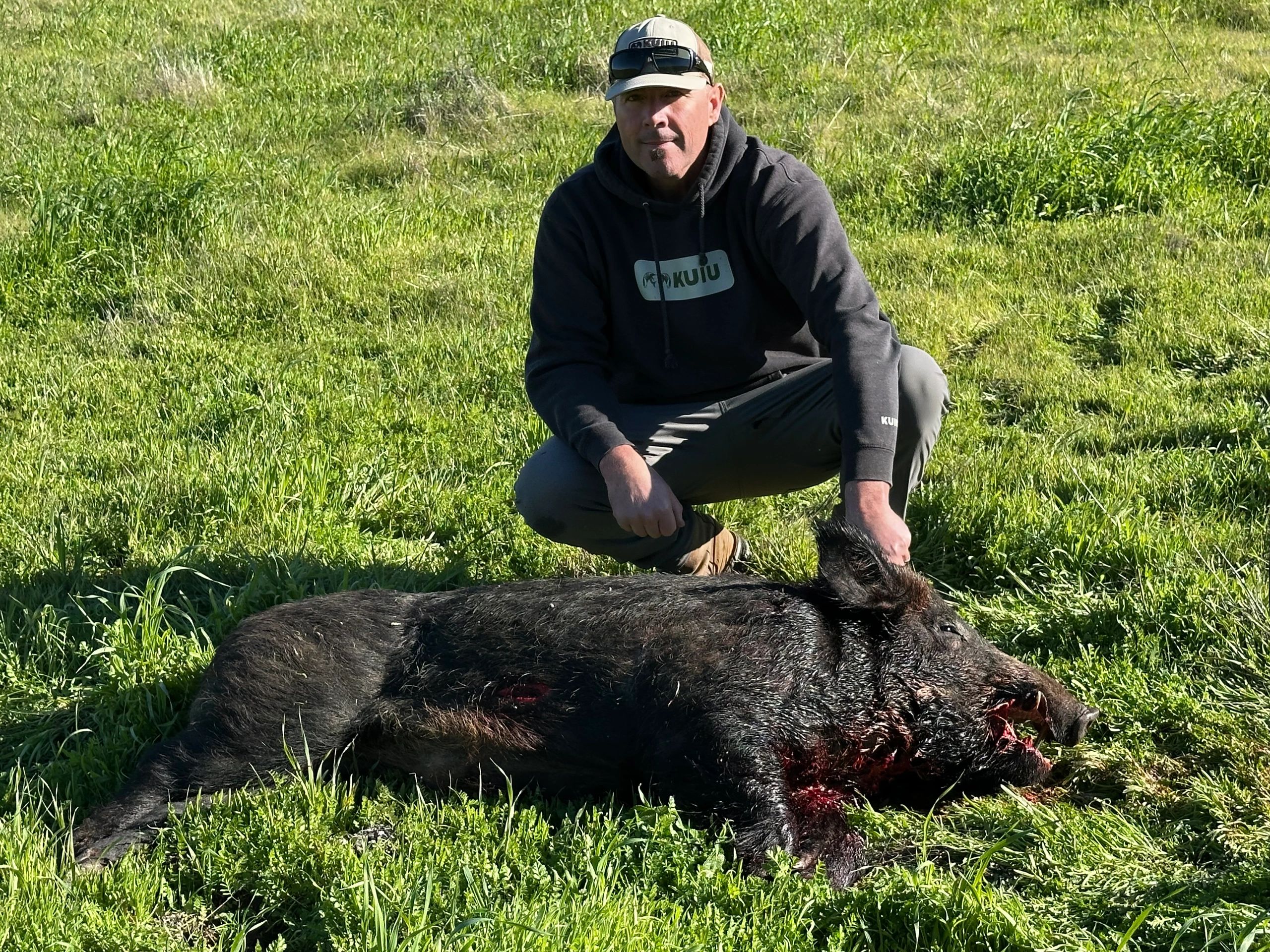 Hunter crouching with harvested wild boar